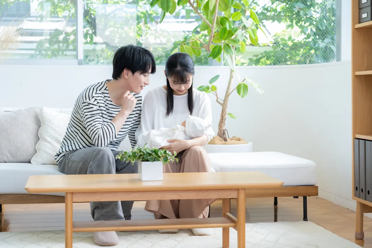 赤ちゃんを抱いてソファに座るご夫婦