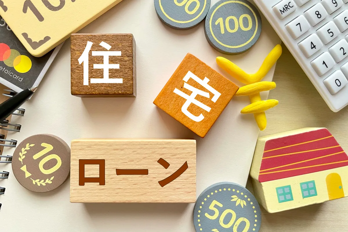 住宅ローンと書かれた積み木と電卓、おうちの模型