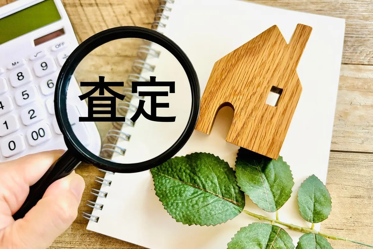 虫めがねで見る「査定」の文字と木のおうち