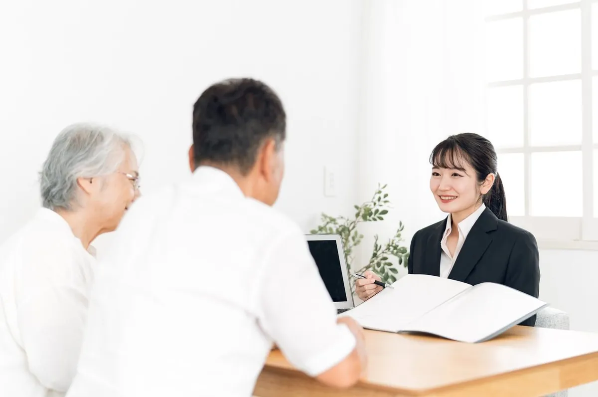 資料を見せながら説明する女性スタッフと年配のご夫婦