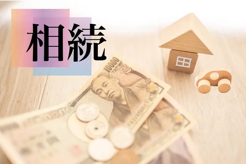 相続の文字と一万円札、木のおうちの模型